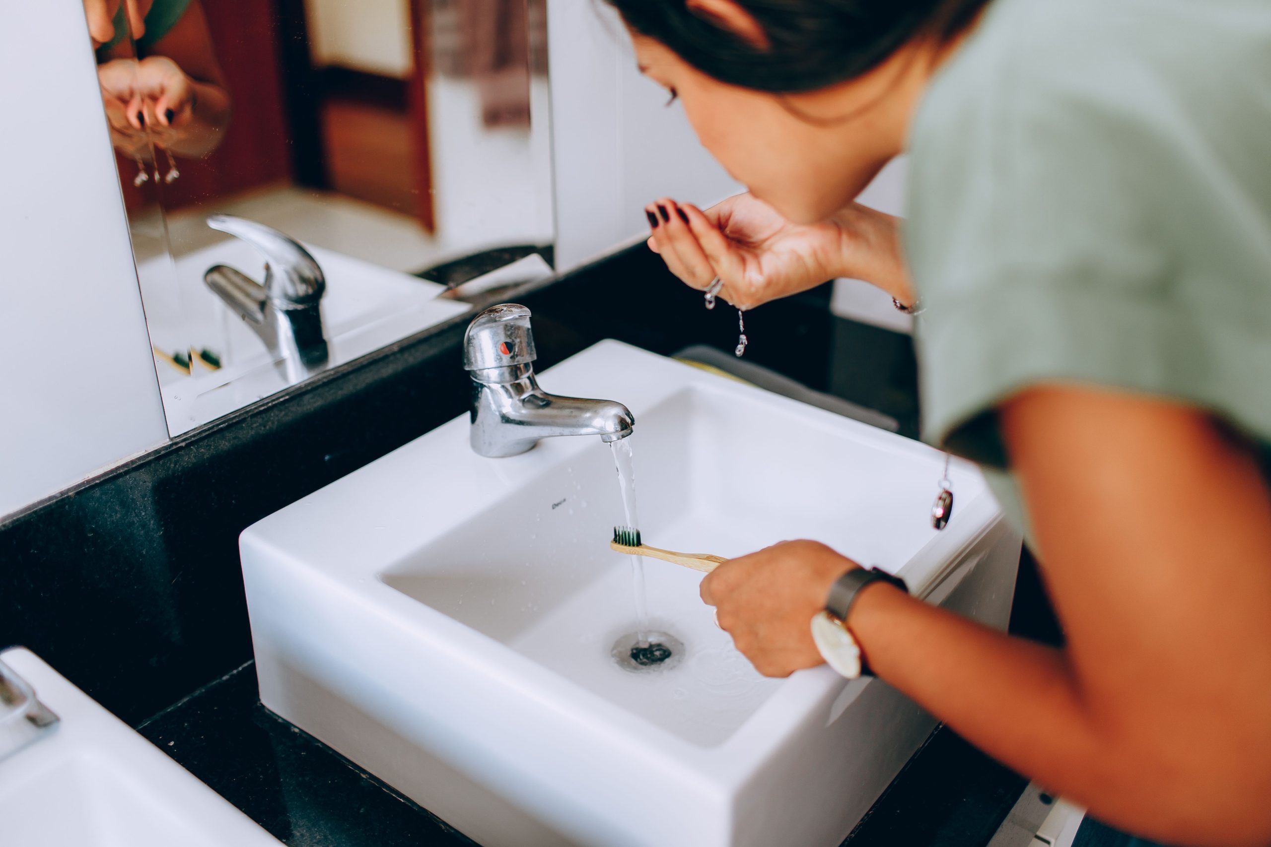 woman rinsing her mouth while holding a toothbrush